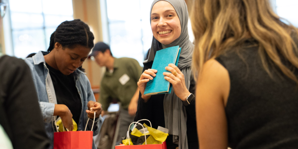 A woman holds a journal while other students look through gift bags.