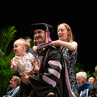 Dentistry Graduate being hooded while holding a baby