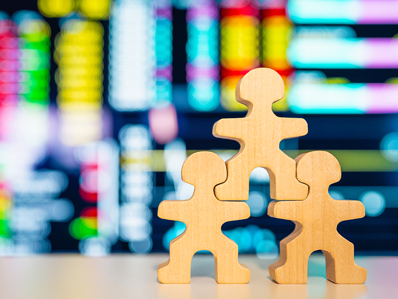 Three wooden figures support one another in a stack