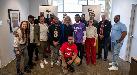 A group of people posing with members of EMBRACE, Dr. Jarrell, and Mayor Brandon Scott