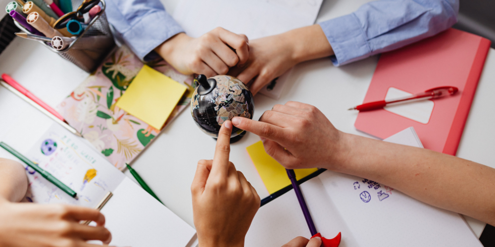 Hands on a desk connecting on a small globe