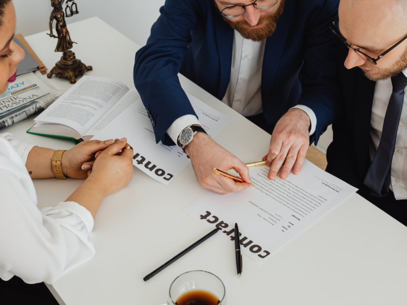 Three people look over a contract.