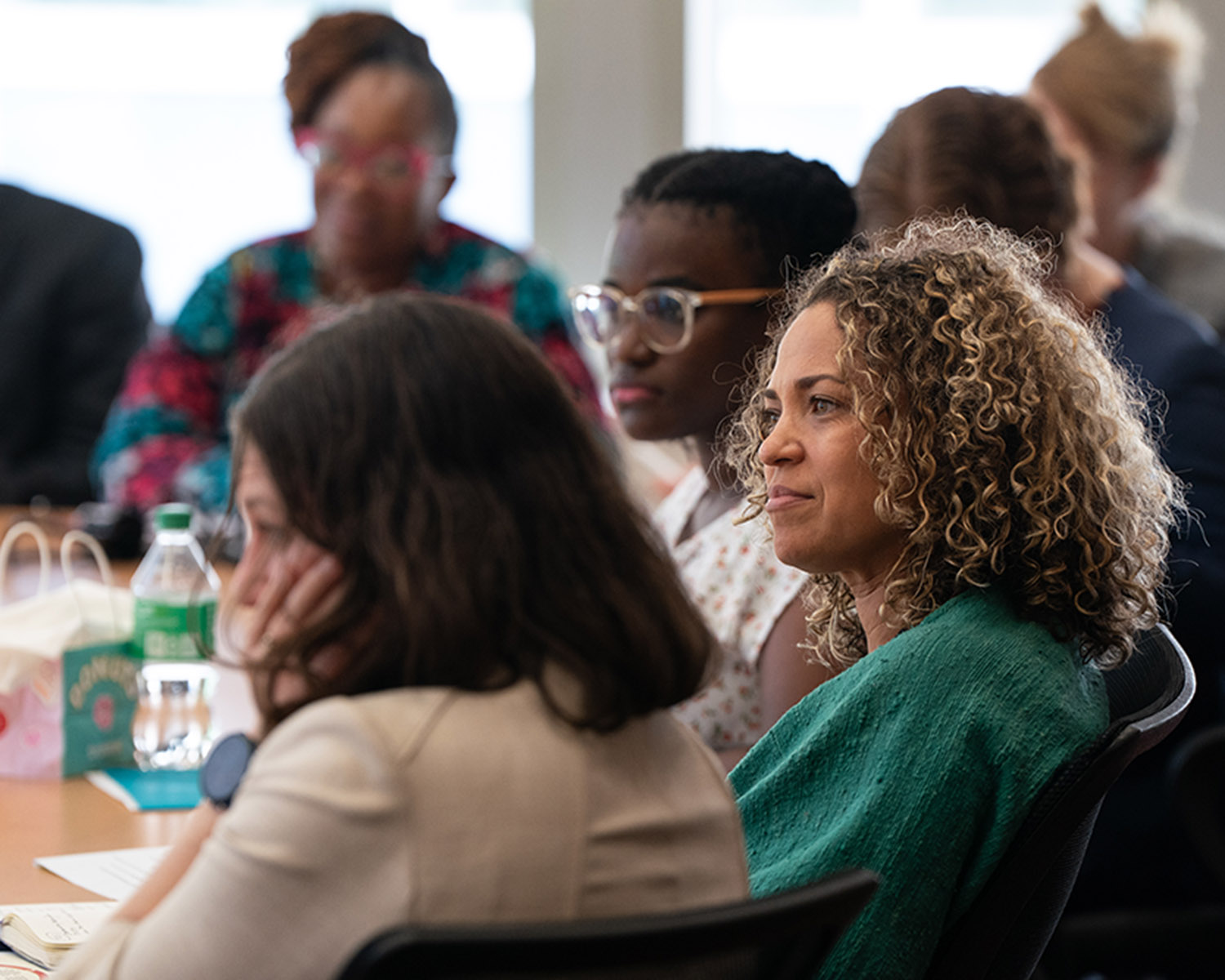 people gathered around a table listening to a presentation