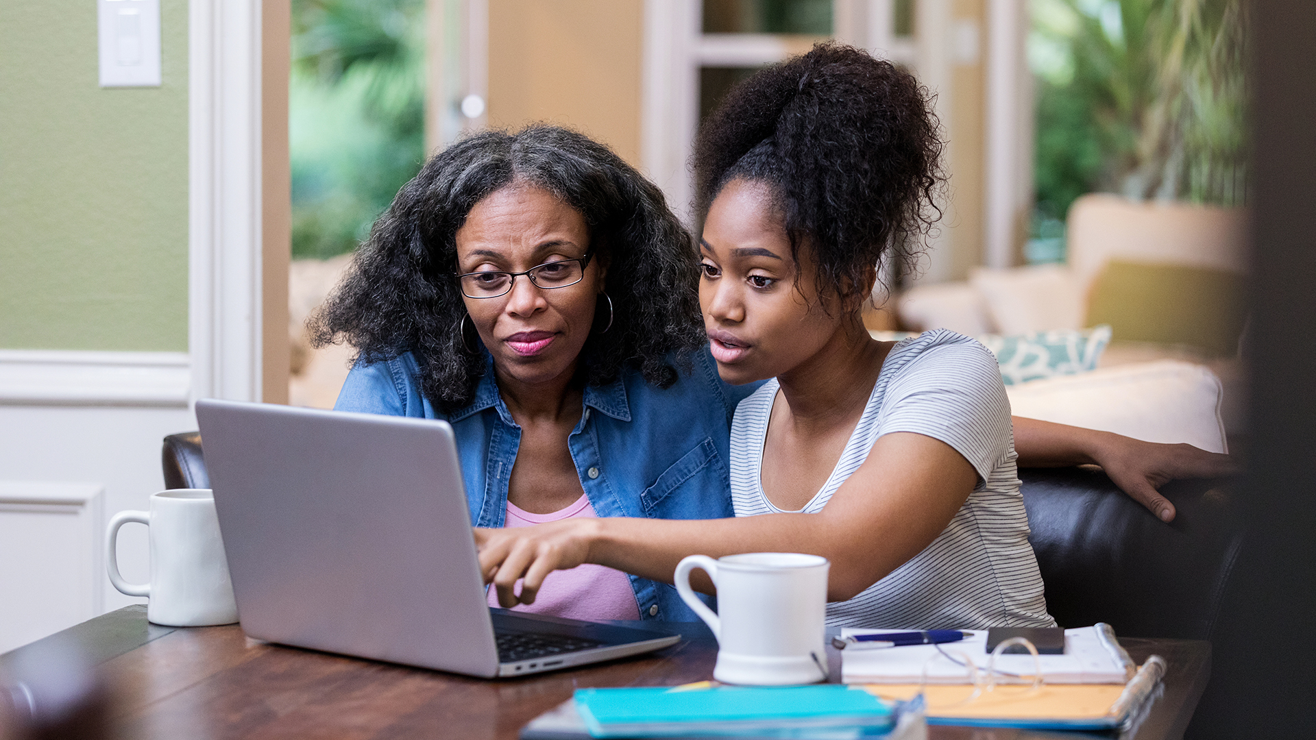 Young woman shows older woman something on laptop
