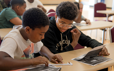 CURE scholars from cohort two study mathematical conversions and ballistics basics during a forensics lab activity.