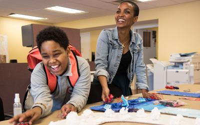University of Maryland School of Social Work student Sara Haile, right, interacts with Tayron Lyons, a participant in UMB’s Police Athletics/Activities League (PAL) program. They are making voting-themed decorations for the Community Engagement Center. 