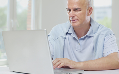 An older man uses a laptop computer.
