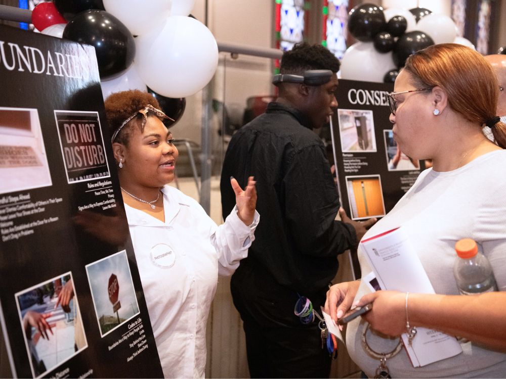 Neveah Boone discusses photos about boundaries with a visitor at the #nofilter exhibit at Westminster Hall.