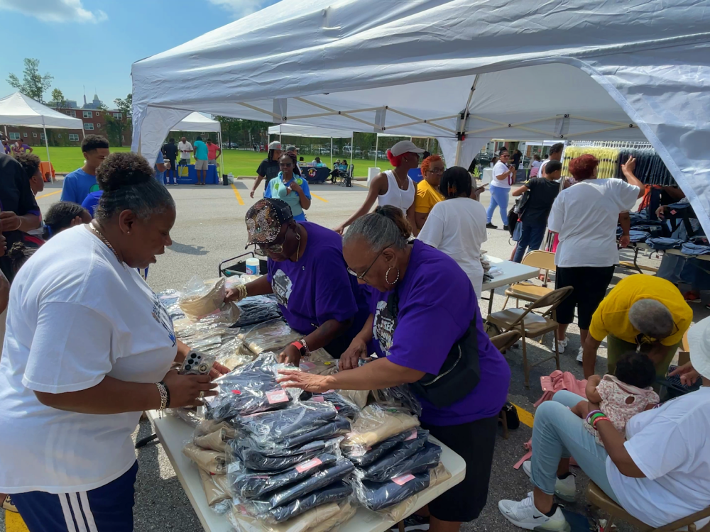 A volunteer at the Fourth Annual Back-to-School Bash searches for a school uniform size for an event attendee.