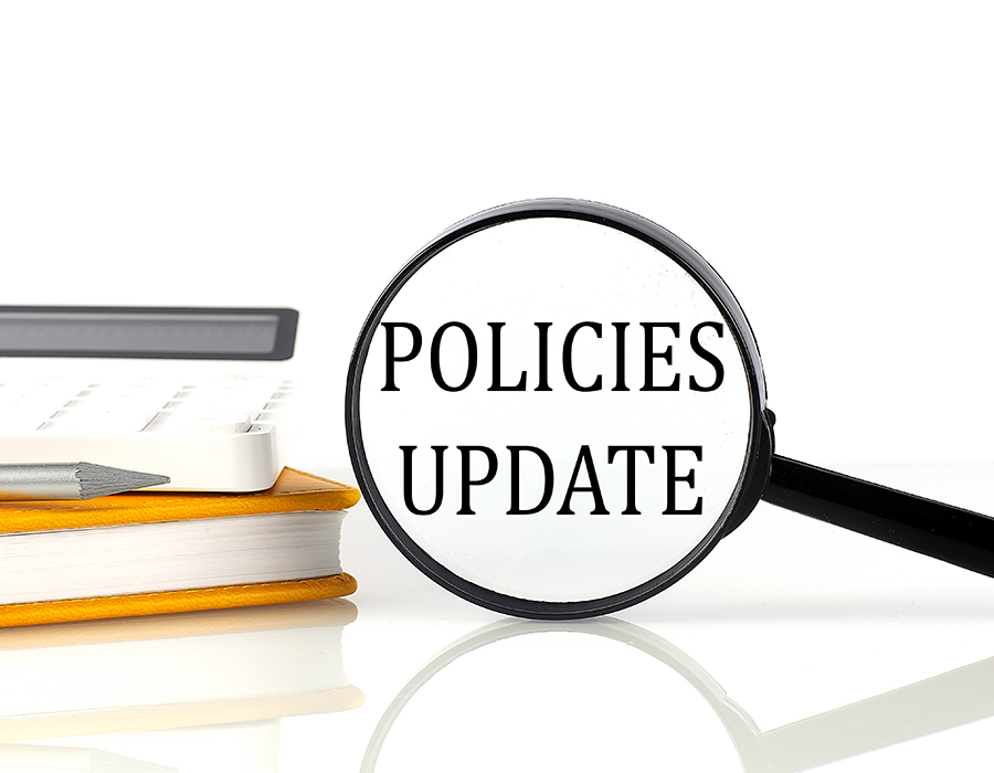 A magnifying glass that says Policies Update, next to a notebook, pencil, and calculator