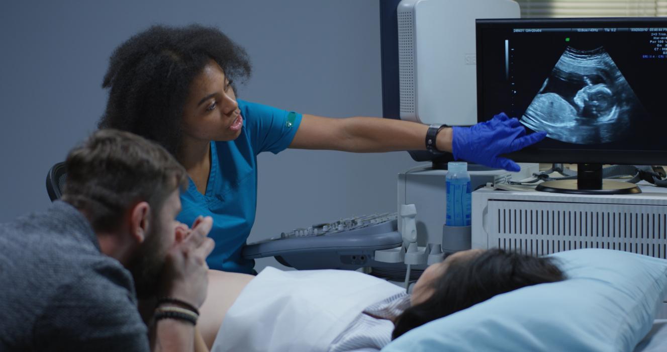 A doctor examines an ultrasound for expecting parents