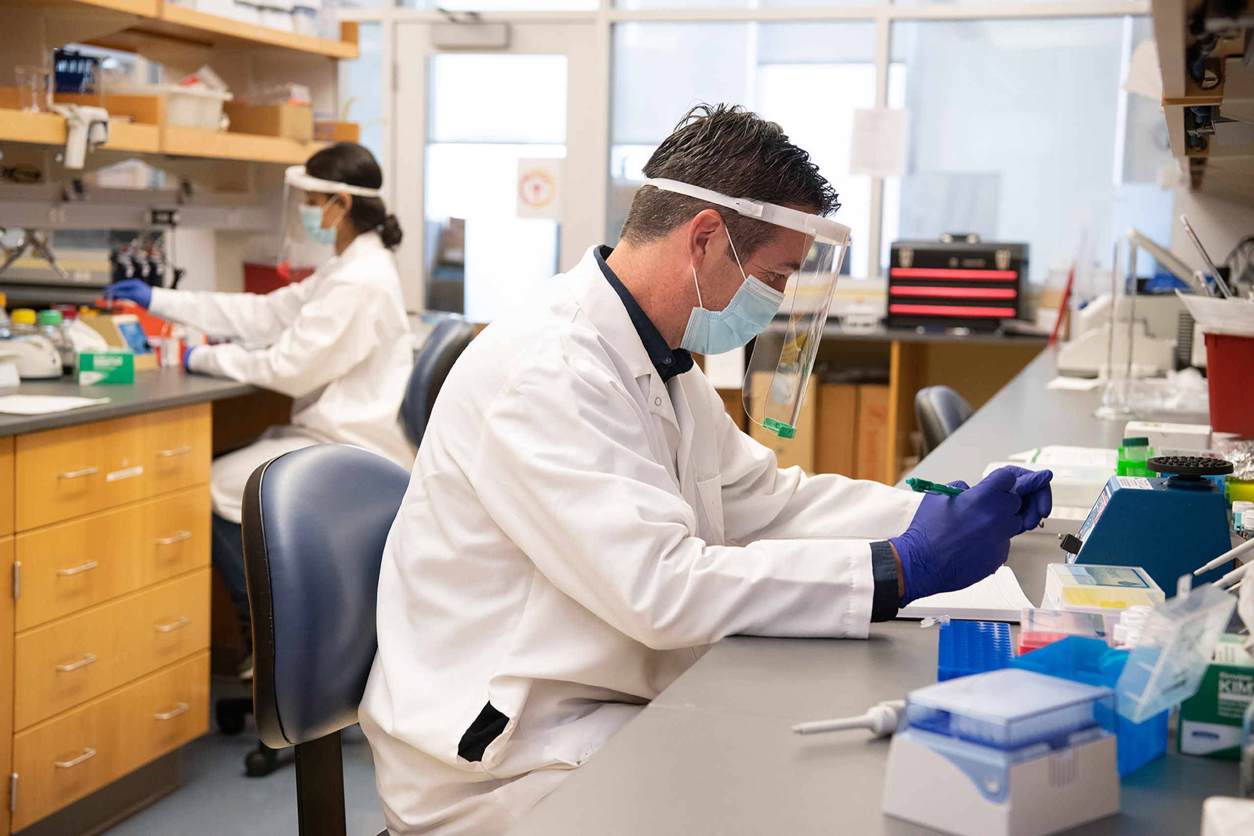 scientist in protective face gear works in a lab